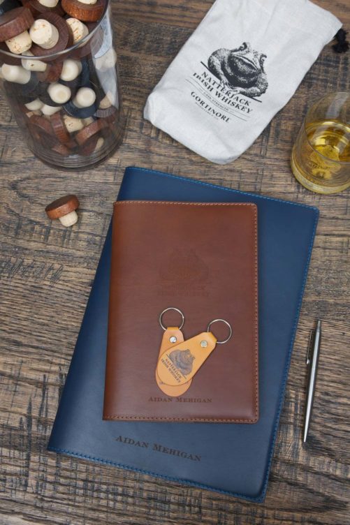 Natterjack Irish Whiskey Keyfob-on-Notebook beside Glass of Whiskey