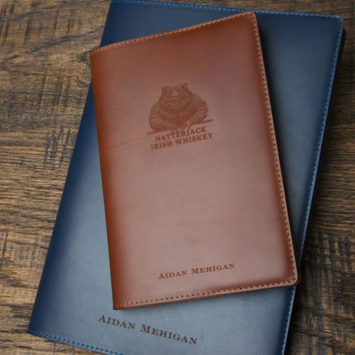 Natterjack Irish Whiskey Leather Tan Notebook on top of Blue Notebook